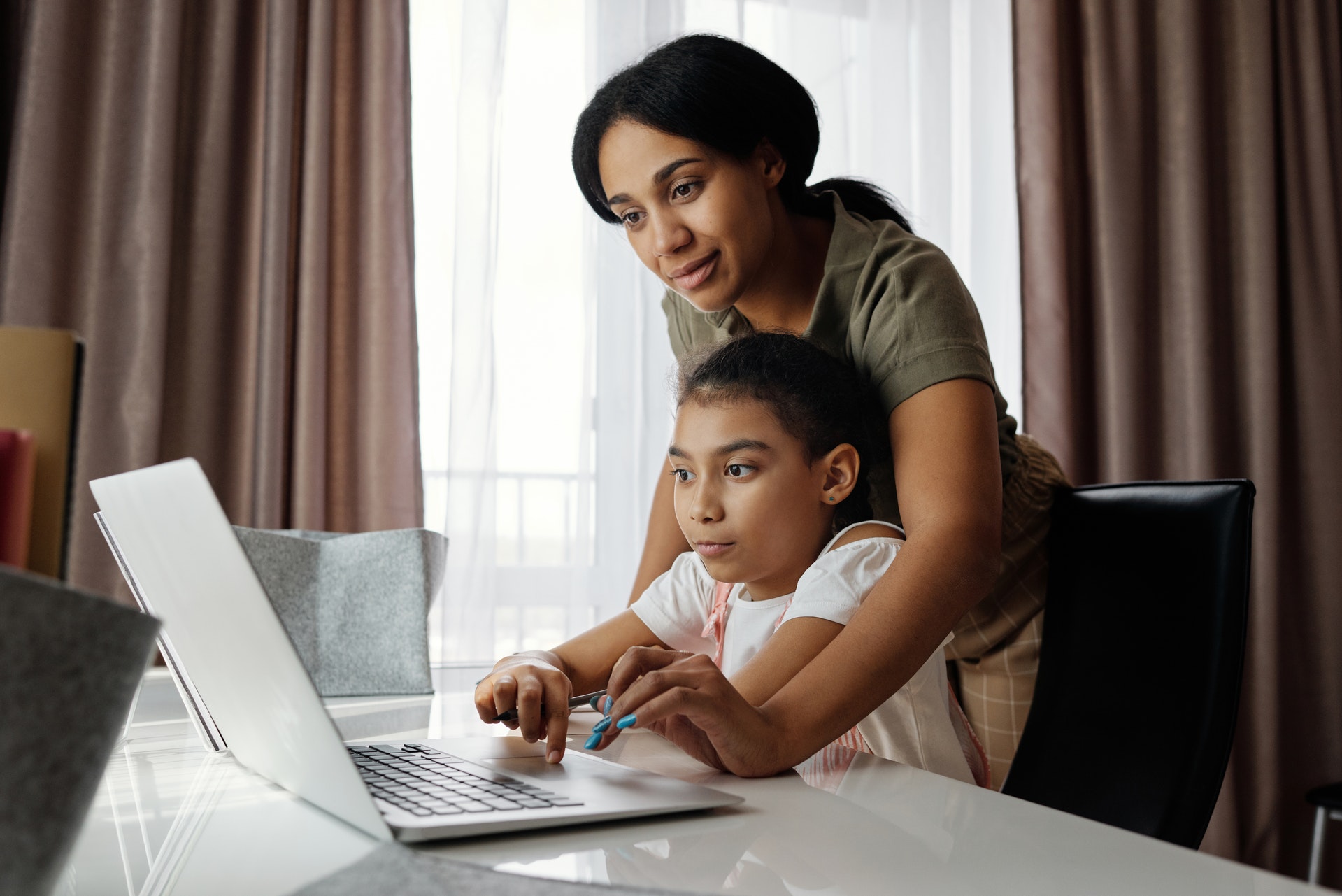 picture of mom helping reading from a computer with daughter